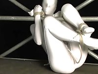 Encased girl in shiny zentai suit is tied to a metal pole and tries to escape